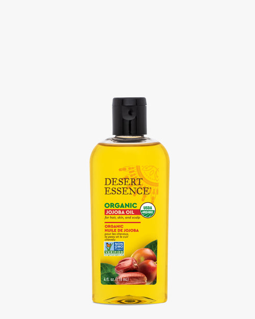 A clear bottle of Organic Jojoba Oil by Desert Essence with golden liquid inside, featuring USDA organic certification and a black cap. The label shows text and natural ingredients imagery against a transparent amber-colored oil.