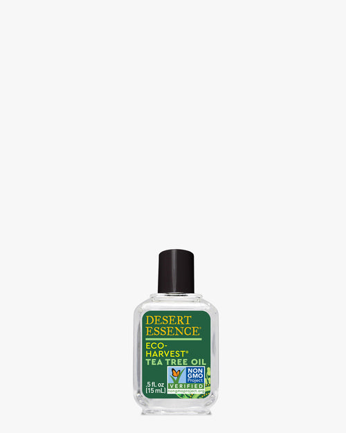 Eco-Harvest Tea Tree Oil, 0.5 Fl Oz bottle with clear liquid, featuring Desert Essence brand label in green and gold colors, displaying Non-GMO certification on a white background. Clear glass container with black cap.