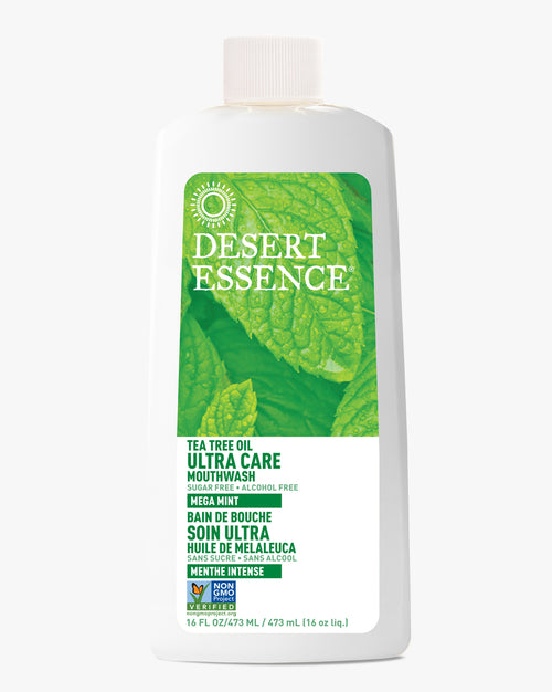 Desert Essence Ultra Care Tea Tree Oil Mouthwash bottle featuring a white plastic container with green leaf design and text elements. Natural oral care product shown against white background with bilingual labeling and non-GMO certification mark.