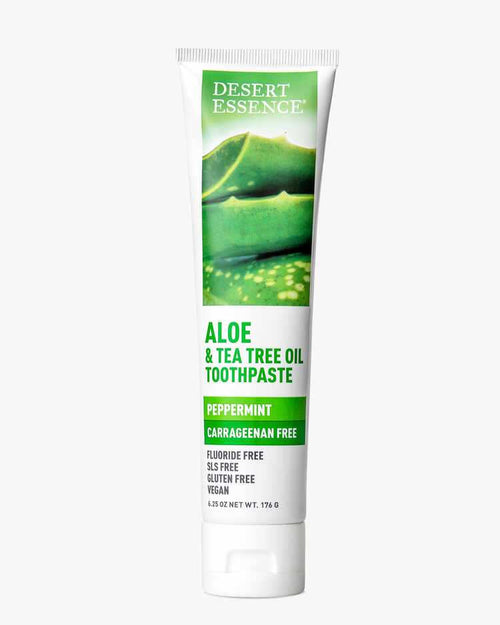 Desert Essence Aloe & Tea Tree Oil Carrageenan Free Toothpaste tube featuring fresh aloe leaf imagery on white background, with green text highlighting natural ingredients and fluoride-free formula. Product in white squeeze tube with peppermint flavor label.