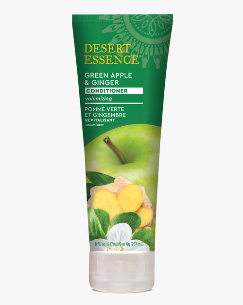 Desert Essence Green Apple & Ginger Conditioner in a white tube with green packaging, featuring vibrant images of fresh green apple and ginger root. Natural hair care product with volumizing formula and bilingual labeling in English and French.