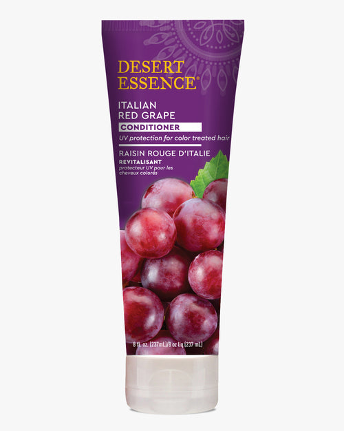 Desert Essence Italian Red Grape Conditioner bottle in purple packaging featuring fresh red grapes. Contains UV protection for color-treated hair. White squeeze tube with gold lettering and vibrant grape imagery.