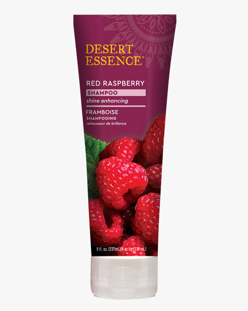 Desert Essence Red Raspberry Shampoo bottle featuring fresh red raspberries on a burgundy background, with gold and white text highlighting shine-enhancing properties and organic ingredients.