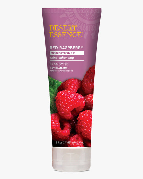 Desert Essence Red Raspberry Conditioner tube featuring fresh red raspberries and green leaves on a purple background, with gold brand lettering and bilingual product information for shine-enhancing hair care