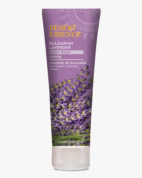 Desert Essence Bulgarian Lavender Body Wash tube in purple packaging featuring vibrant lavender flower illustrations, with gold brand lettering and bilingual product information on a clean white background