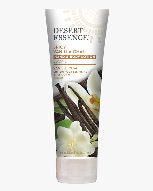 Desert Essence Spicy Vanilla Chai Hand & Body Lotion tube with vanilla flowers and cinnamon sticks decorating the label, displaying organic skincare product against white background in uplifting design