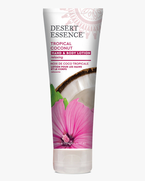 Desert Essence Tropical Coconut Hand & Body Lotion tube featuring a pink hibiscus flower and coconut imagery on white packaging. The organic moisturizing lotion bottle displays bilingual text in English and French with relaxing properties.