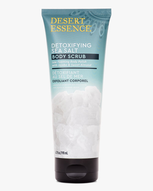 Desert Essence Detoxifying Sea Salt Body Scrub tube in soft turquoise packaging showing natural exfoliating formula with almond and jojoba oils for smooth, glowing skin