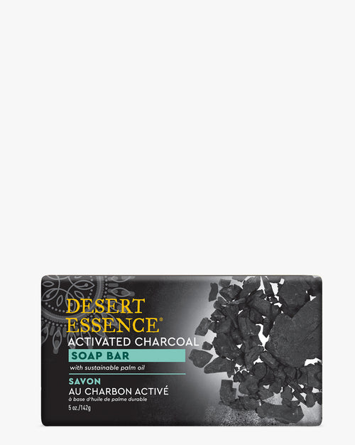 Activated Charcoal Soap Bar by Desert Essence with scattered black charcoal fragments on dark packaging, featuring teal accents and text highlighting sustainable palm oil ingredients