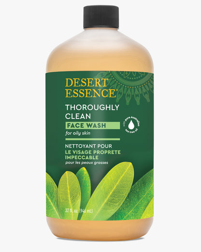 Desert Essence Thoroughly Clean Face Wash Refill bottle with green label and tea tree leaf design, containing natural face cleanser with Tea Tree Oil and Castile Soap. Large amber-colored plastic bottle features green botanical elements and bilingual text.