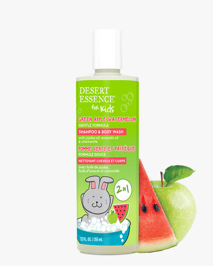 Desert Essence Green Apple Watermelon Kids 2in1 Shampoo & Body Wash bottle with bright green label featuring cartoon bunny illustration, displayed alongside fresh watermelon slice and green apple, showcasing natural ingredients and gentle formula for children