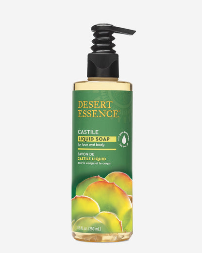 Tea Tree Oil Liquid Castile Soap in a clear pump bottle with Desert Essence branding, featuring a green label and citrus fruit imagery. The natural liquid soap appears golden-amber in color, showcasing its olive oil and coconut oil base.