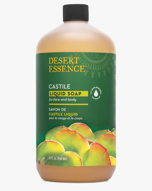 Tea Tree Oil Liquid Castile Soap Refill by Desert Essence in a large amber plastic bottle with green label featuring peach illustrations, containing natural face and body cleanser with olive oil and eco-harvest tea tree oil