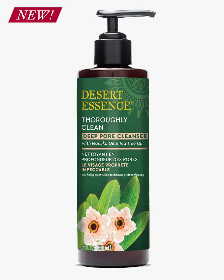 Desert Essence Thoroughly Clean Deep Pore Cleanser bottle in dark brown with green label featuring delicate pink flowers and green leaves. NEW banner in red. Product features pump dispenser and bilingual text highlighting Manuka and Tea Tree Oil ingredients.