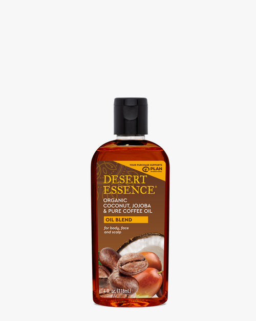 Desert Essence Organic Coconut, Jojoba & Coffee Oil blend in a clear bottle with amber-colored liquid, featuring ingredients imagery of coconut and coffee beans on white background. Professional product photography of natural skincare oil for body, face and scalp use.